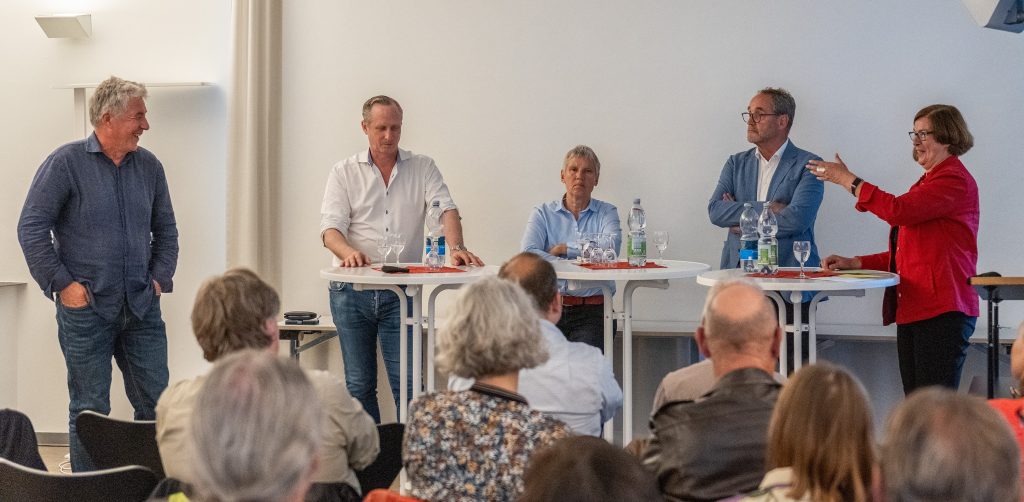 Diskussion im Architekturforum Freiburg zum Thema Industriedenkmäler und Zukunft der Stadtentwicklung - Diskussion auf einer Veranstaltung - Das Bild zeigt eine aktuelle Veranstaltung oder ein Projekt des Architekturforums Freiburg, das sich mit der Zukunft von Industriedenkmälern und Brachflächen beschäftigt. Es visualisiert den Dialog zwischen Architektur, Stadtentwicklung und Nachhaltigkeit, typischerweise mit Fachleuten, Besuchern oder Architekturmodellen im Hintergrund.