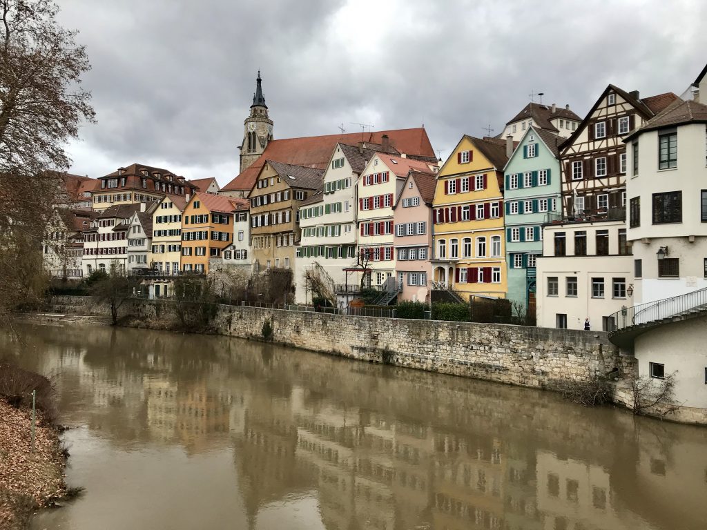 Farbige Häuser am Flussufer -Das Bild zeigt einen pittoresken Straßenzug in Bamberg, wahrscheinlich aus dem historischen Sandgebiet mit engen Gassen, traditionellen Fachwerkhäusern und Palais unter Denkmalschutz. Es illustriert den UNESCO-Weltkulturerbe-Status der Bamberger Altstadt mit charakteristischen Bauepochen.