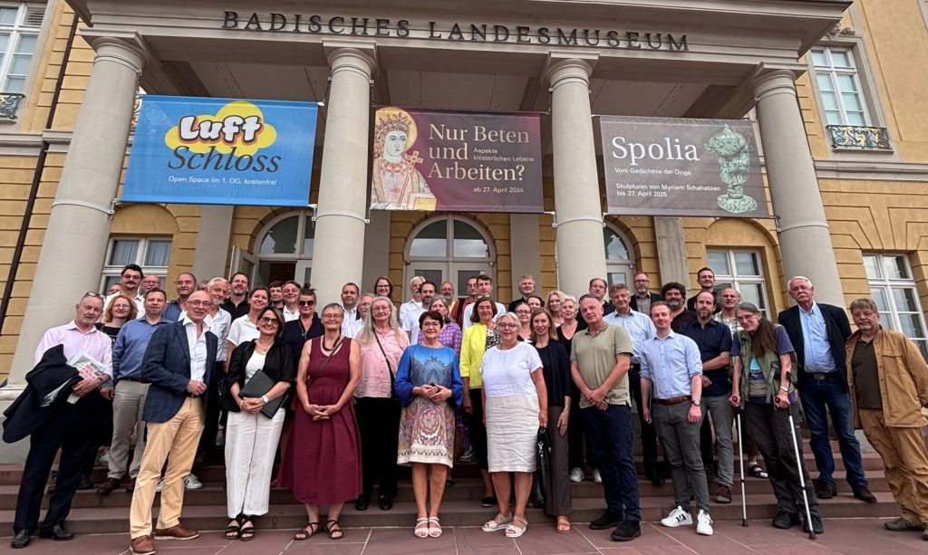 Das Bild zeigt einen Moment aus der Gründung des DenkmalnetzBW, dem Dachverband für Denkmalschutz und Denkmalpflege in Baden-Württemberg, bei dem Experten, Vertreter und Interessierte die Zusammenarbeit für den Erhalt historischer Gebäude feiern. Gründung DenkmalnetzBW: Experten und Vertreter im Austausch zum Denkmalschutz in Baden-Württemberg