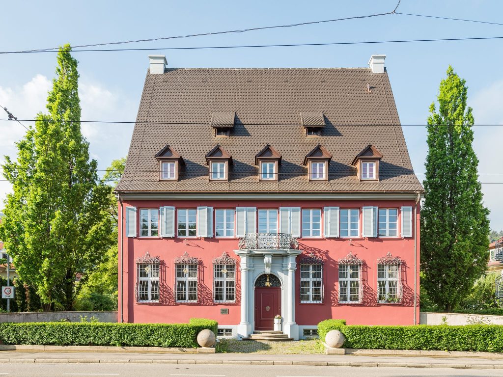 Das Bild zeigt das sanierte Gebäude des Vereins "Badische Heimat" in Freiburg nach energetischer Sanierung: Späthistoristische Fassade der 1920er Jahre mit erhaltenen Gesimsen, neuer Dachdeckung und Dämmung – Demonstration von substanzschonender Modernisierung ohne Verlust architektonischer Merkmale. Badische Heimat Freiburg sanierte Fassade energetische Sanierung Baukultur Denkmalschutz Grundmann Wiedemann.